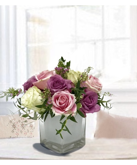 Pink, lavender and white roses in a white glass vase.