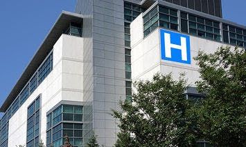 A modern hospital building with large windows and a prominent blue 